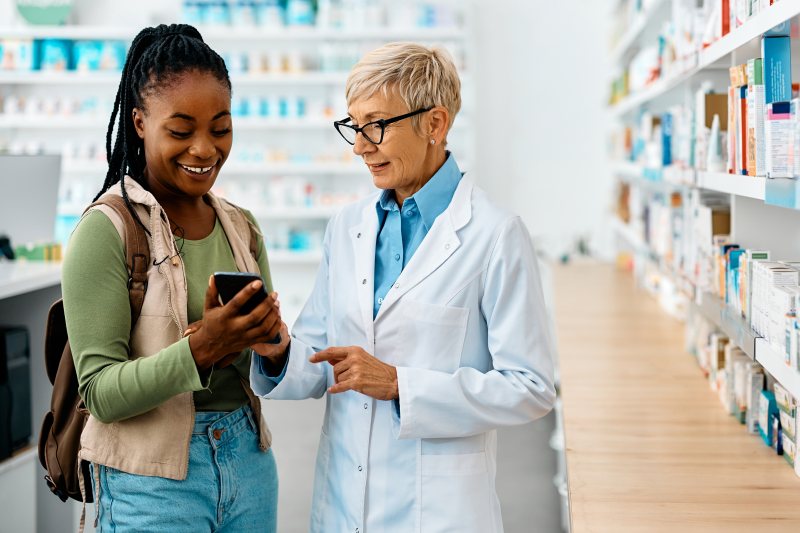 A pharmacist helping a member with her phone at the pharmacy counter